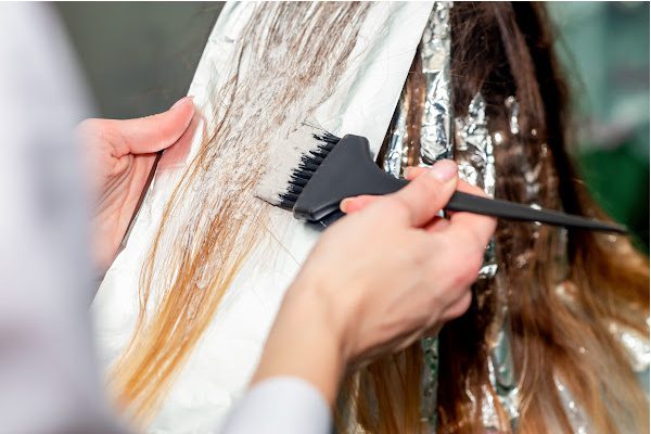 Woman getting hair highlighted at salon