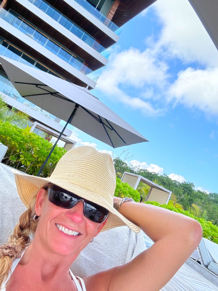 Founder Lori Parsons sitting poolside on a sunny day at Impression Moxché in Playa Del Carmen in Mexico.