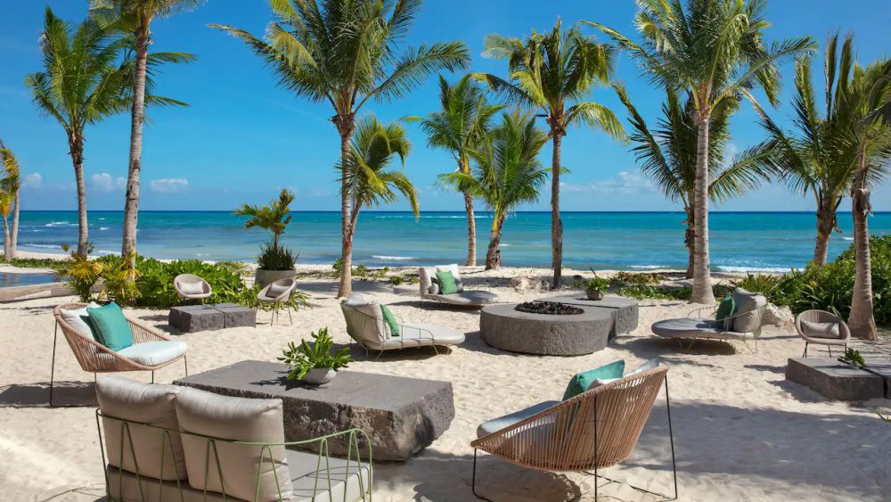 Outdoor seating area at the Seaside Club Restaurant at, which is indoor / outdoor beside the ocean at Impressions Moxché, with cozy chairs and a firepit.